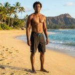 Man in black HIC Generals board shorts standing on the beach