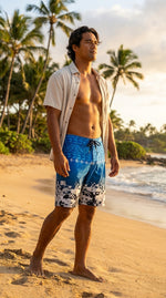 Man in an open shirt on a palm-lined beach in HIC Digital Coast board shorts