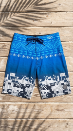 HIC Digital Coast board shorts laid flat on wood, showing the Polynesian band and the pixel print at the hem