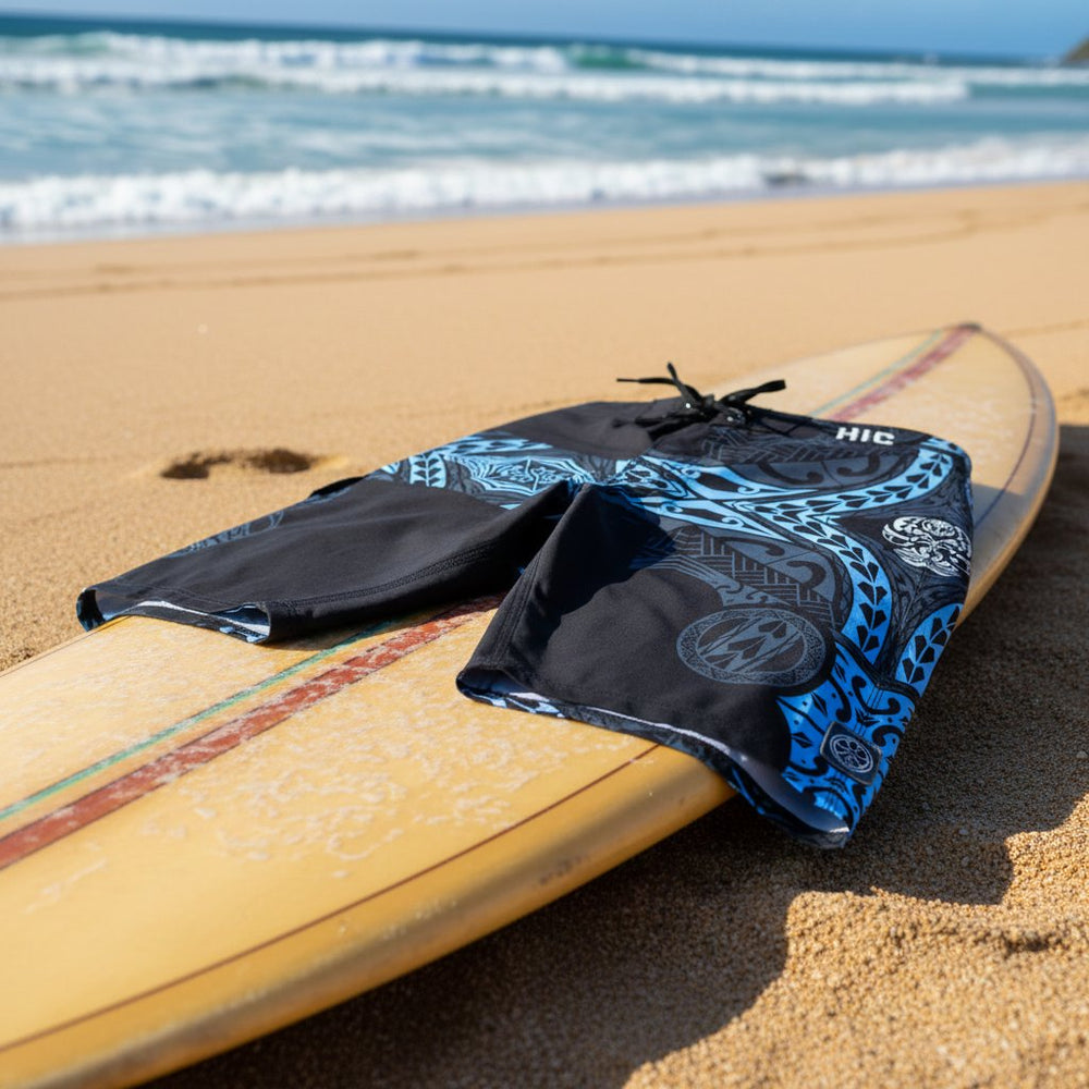 HIC Kanaha 21-inch board shorts in Black Sky laid on a surfboard on the beach
