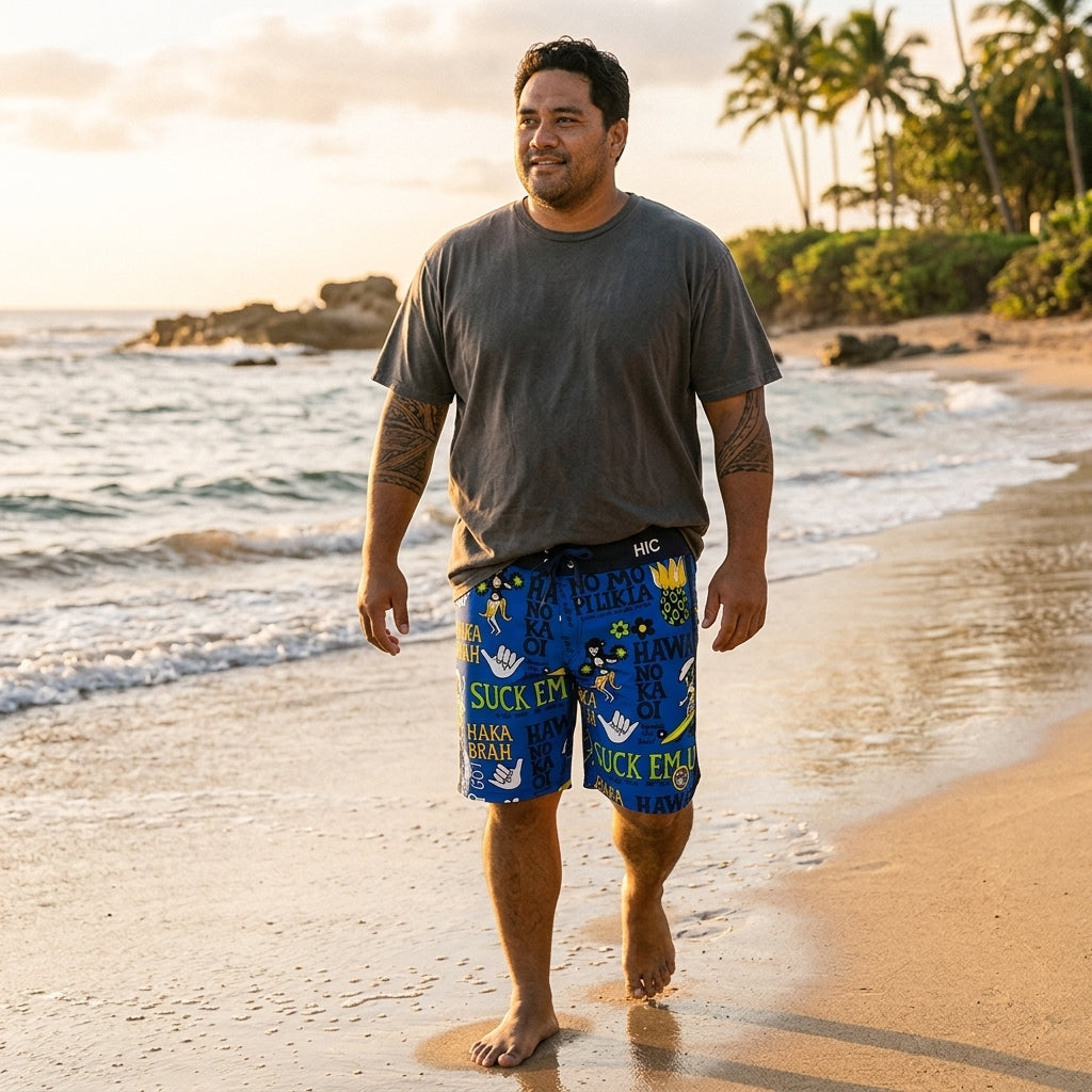 Man in a gray T-shirt walking the shoreline in HIC Suck Em Up board shorts